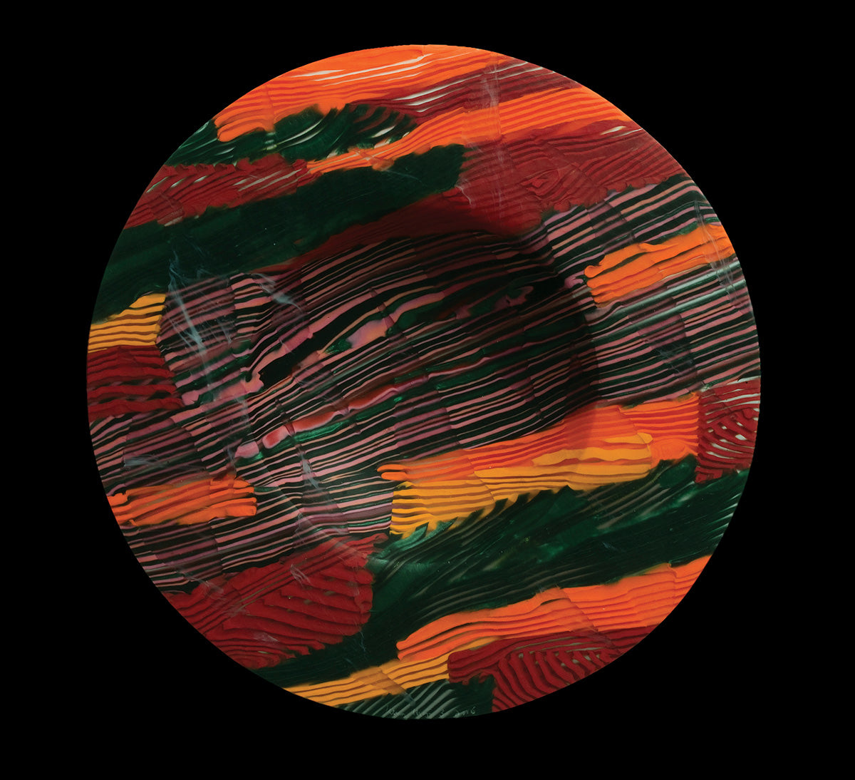 A bowl with abstract patterning in red, orange and green by artist Klaus Moje
