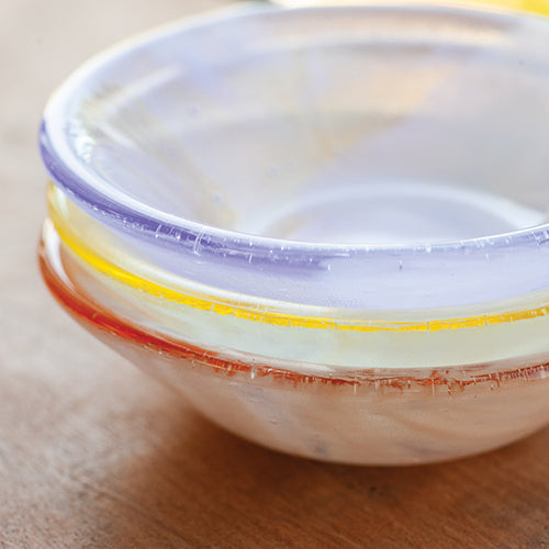 Stack of colorful glass bowls on a wooden surface