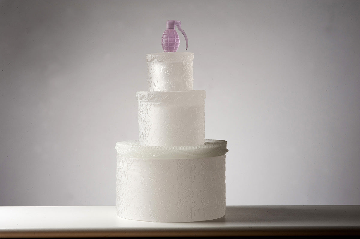 silvia levensen's artwork, a white glass cake with pink glass hand grenade on top